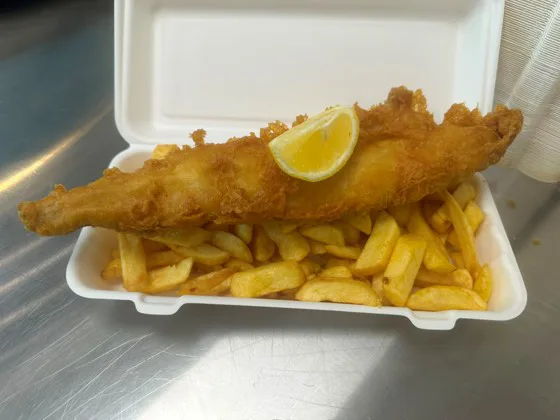 Fish and chips with a wedge of lemon on the counter